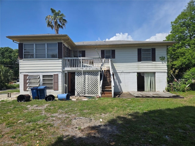 rear view of property with stairway, a wooden deck, and a lawn