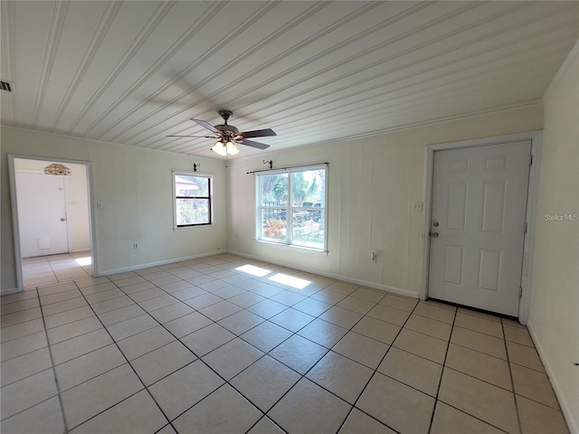 spare room with crown molding, ceiling fan, visible vents, light tile patterned flooring, and baseboards