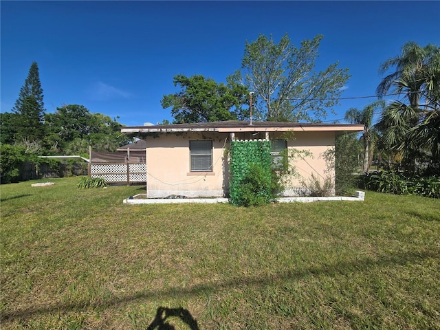 back of house featuring stucco siding and a lawn