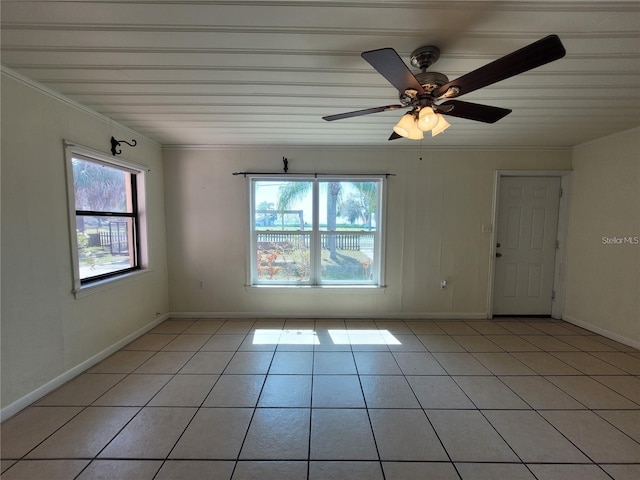 spare room with a ceiling fan, light tile patterned flooring, baseboards, and ornamental molding
