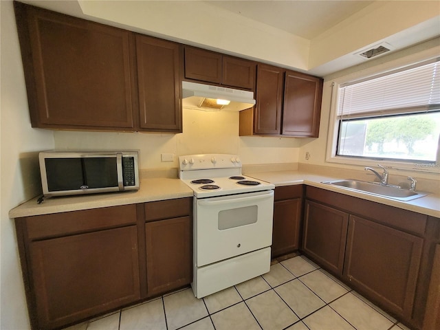 kitchen featuring stainless steel microwave, white electric stove, under cabinet range hood, visible vents, and a sink
