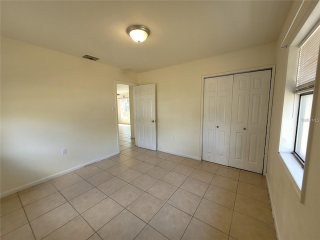 unfurnished bedroom featuring a closet, baseboards, visible vents, and light tile patterned floors
