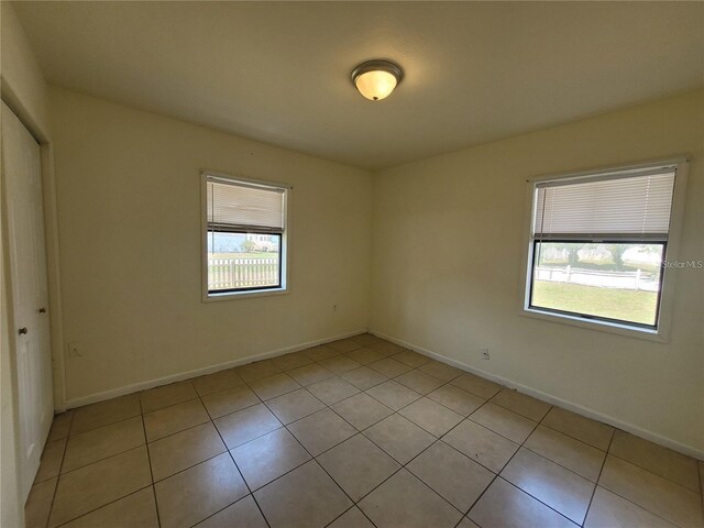 empty room with light tile patterned floors and baseboards