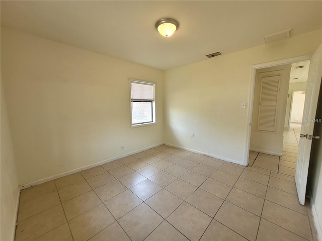 empty room featuring light tile patterned floors, visible vents, and baseboards