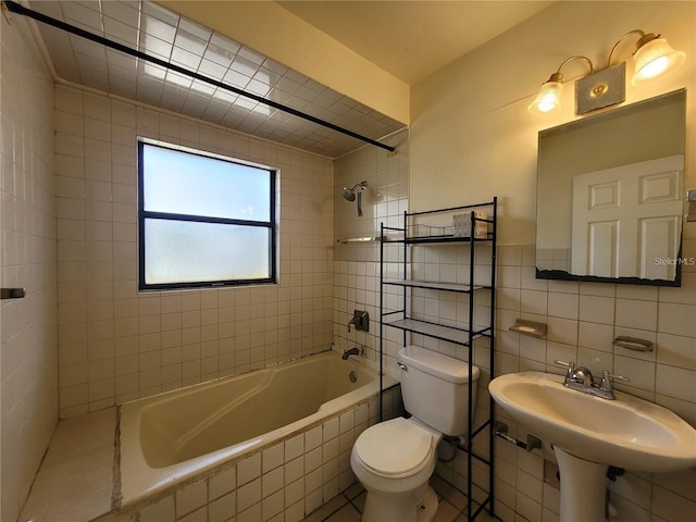 bathroom featuring toilet, backsplash, tile walls, and tiled shower / bath
