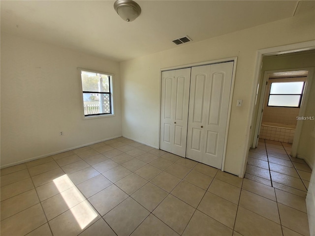 unfurnished bedroom featuring a closet, light tile patterned floors, baseboards, and visible vents