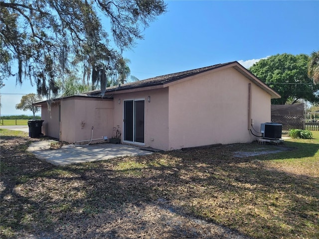 back of house with a lawn, a patio area, central AC, and stucco siding