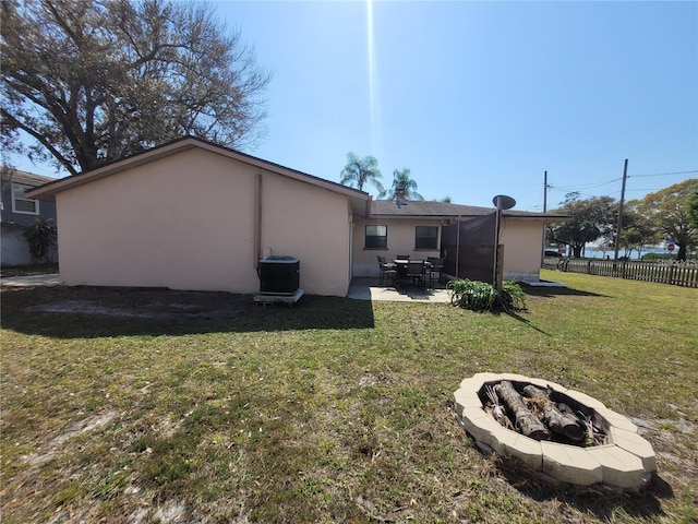 back of property featuring a yard, stucco siding, an outdoor fire pit, a patio, and fence