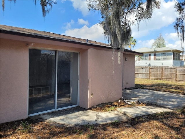 view of property exterior featuring a patio, stucco siding, and fence
