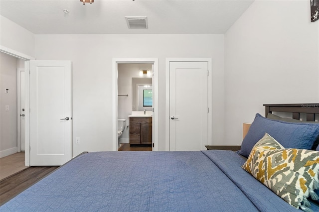 907 Arlington Ave N, Saint Petersburg, FL 33705 - bedroom with baseboards, connected bathroom, visible vents, and wood finished floors