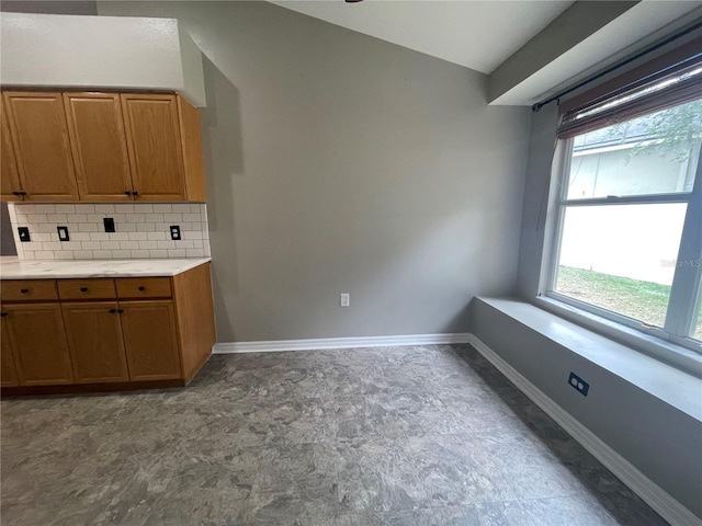 4731 Portobello Cir, Valrico, FL 33596 - kitchen with brown cabinetry, backsplash, light countertops, and baseboards