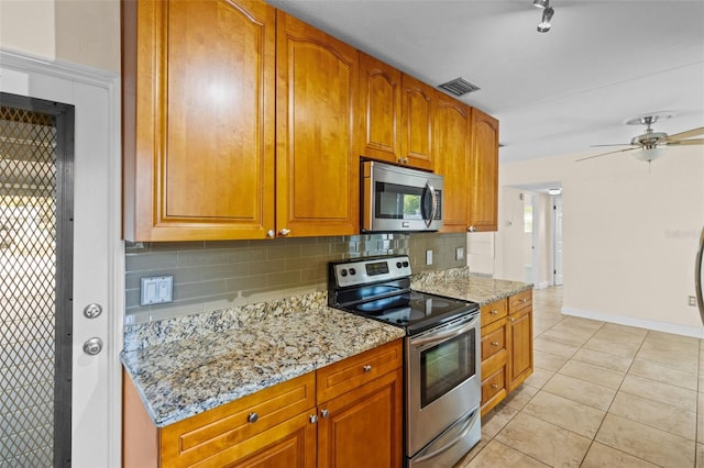1411 Barry St, Clearwater, FL 33756 - kitchen featuring light tile patterned floors, light stone countertops, stainless steel appliances, and decorative backsplash