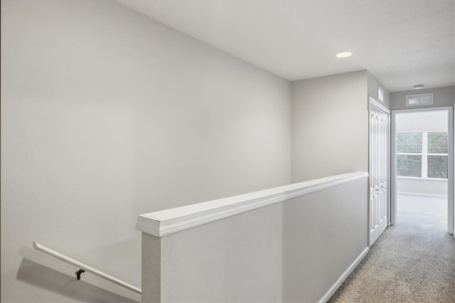 hall with an upstairs landing, carpet, and baseboards