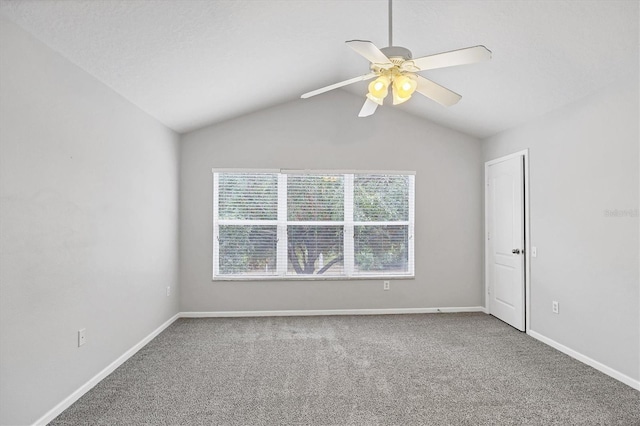 empty room featuring carpet flooring, baseboards, ceiling fan, and vaulted ceiling