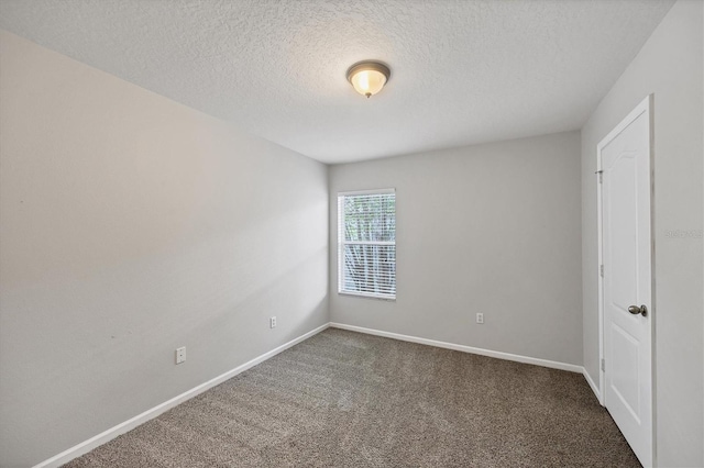 unfurnished room with carpet, baseboards, and a textured ceiling