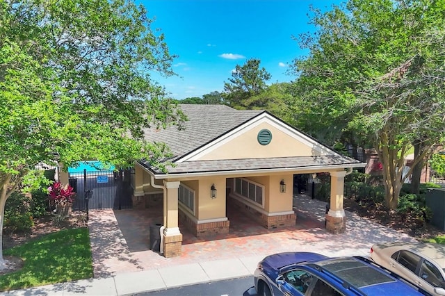 view of front facade with roof with shingles, fence, stucco siding, and uncovered parking