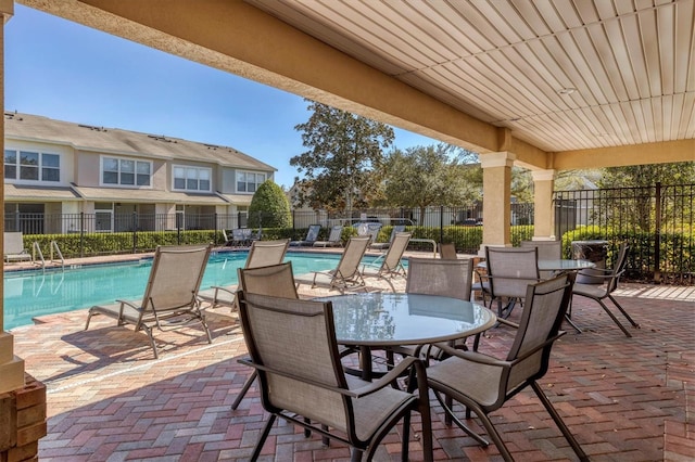 view of patio with a community pool and fence
