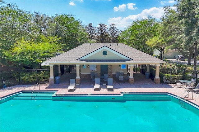 community pool with fence, a patio, and view of scattered trees