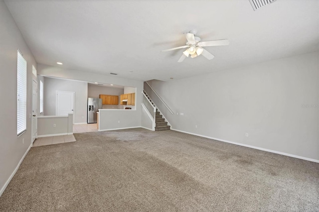 unfurnished living room with light colored carpet, a ceiling fan, stairs, baseboards, and recessed lighting