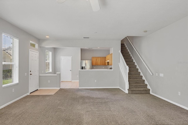 unfurnished living room featuring light colored carpet, stairs, plenty of natural light, and baseboards