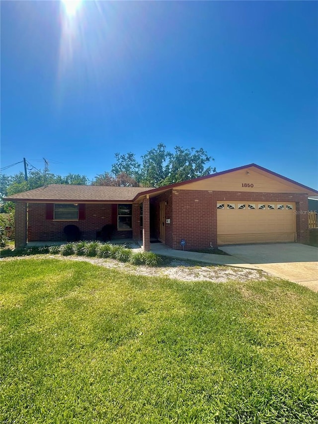 ranch-style home featuring driveway, brick siding, a garage, and a front yard