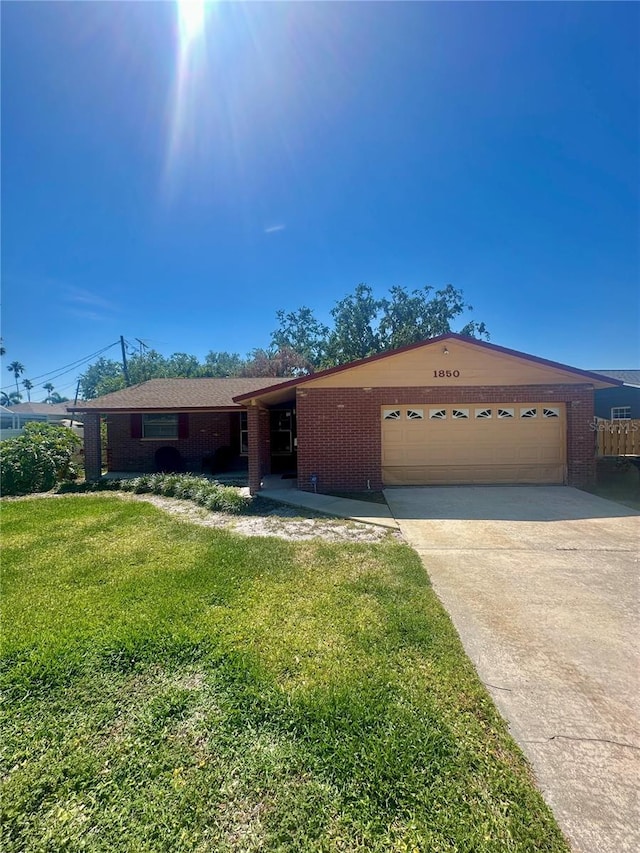 single story home with a front lawn, driveway, an attached garage, and brick siding
