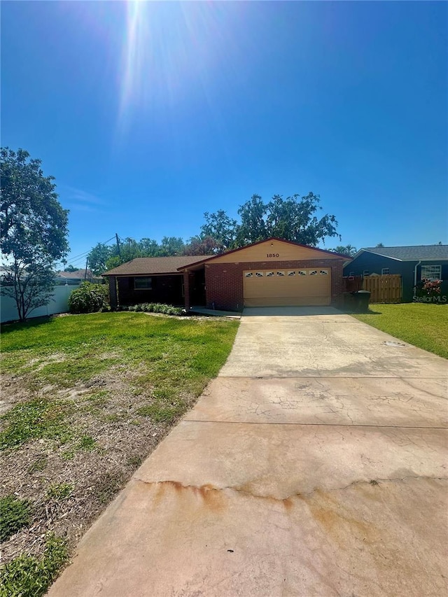 ranch-style house with a front yard, driveway, a garage, and fence
