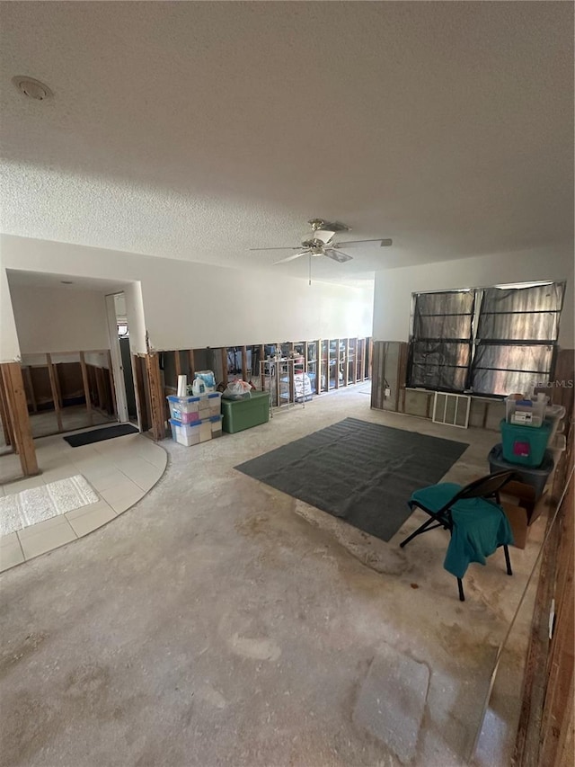 unfurnished living room featuring unfinished concrete flooring, a textured ceiling, and ceiling fan