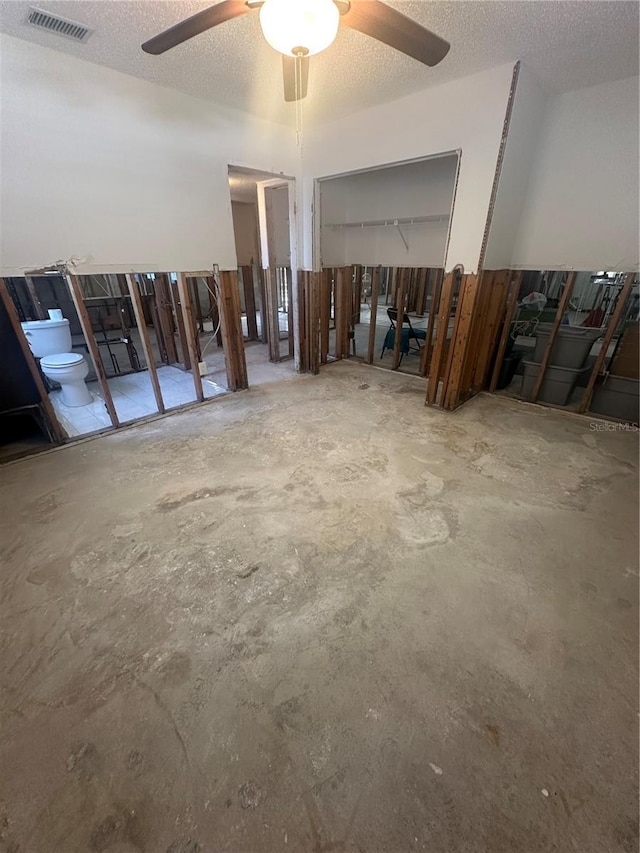 miscellaneous room featuring unfinished concrete flooring, a textured ceiling, visible vents, and a ceiling fan