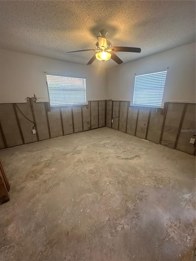 unfurnished room featuring a textured ceiling, unfinished concrete floors, and ceiling fan