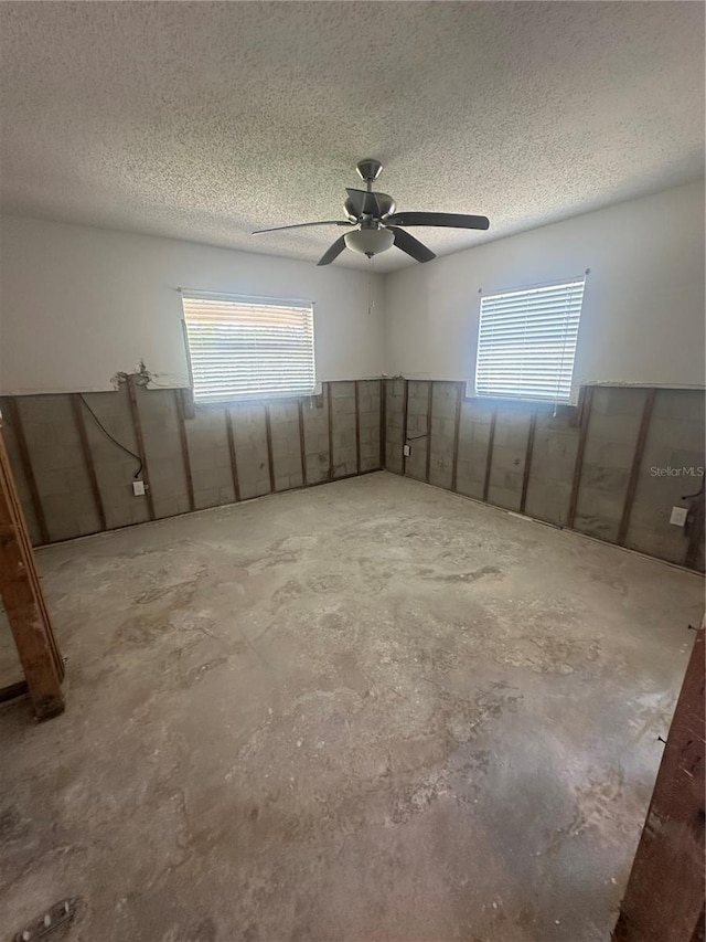 unfurnished room with a ceiling fan, a healthy amount of sunlight, and a textured ceiling