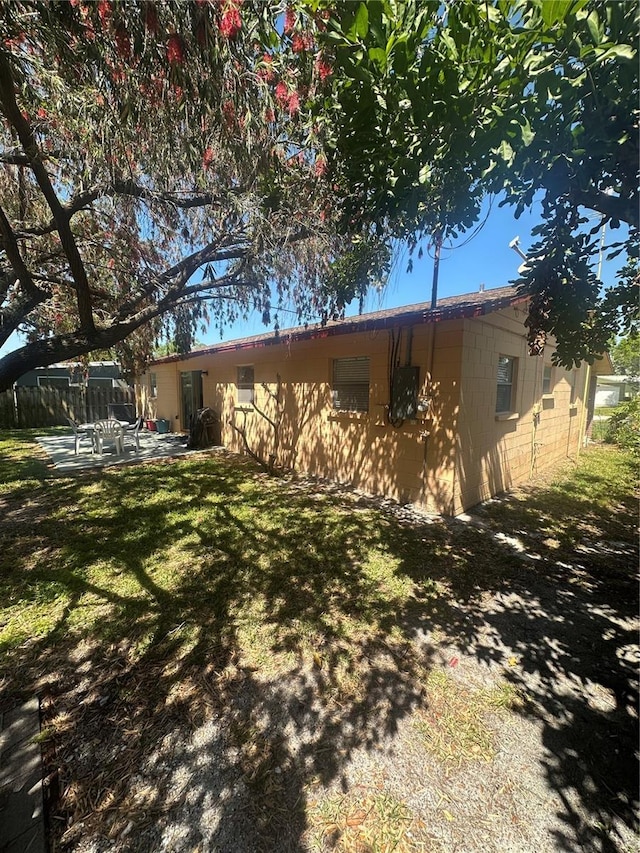 exterior space with a patio, fence, a yard, and concrete block siding