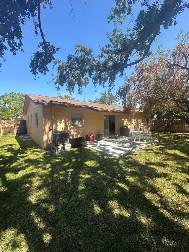back of property featuring a lawn, central AC unit, fence, and a patio area