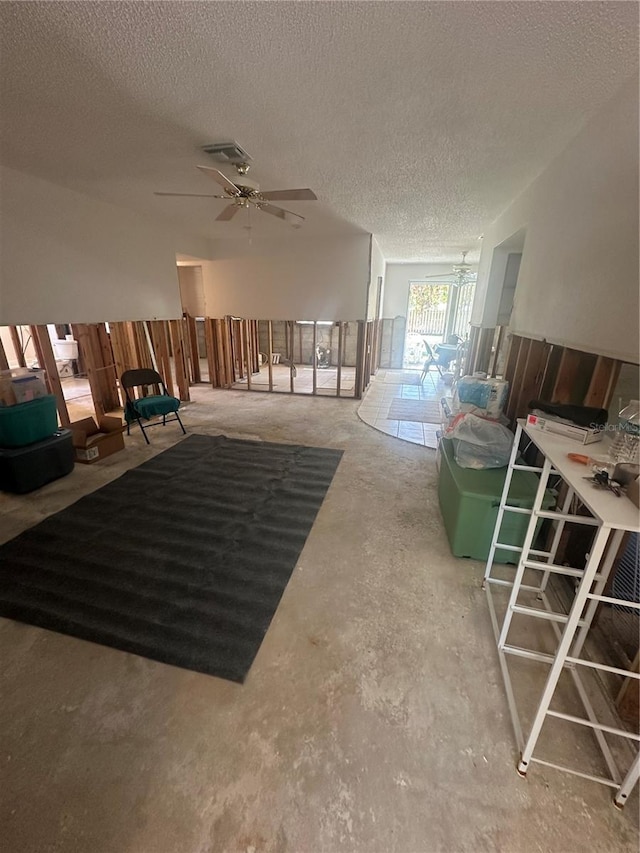 miscellaneous room with unfinished concrete flooring, visible vents, ceiling fan, and a textured ceiling