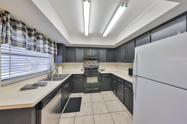 kitchen featuring light countertops, under cabinet range hood, a sink, light tile patterned flooring, and appliances with stainless steel finishes