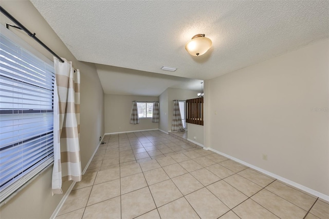 unfurnished room featuring baseboards, visible vents, a textured ceiling, and light tile patterned floors