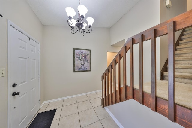 foyer entrance featuring baseboards, stairs, an inviting chandelier, and light tile patterned floors