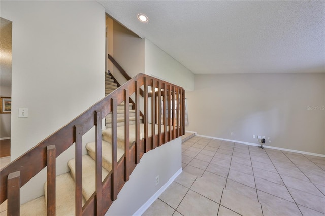 staircase with baseboards, lofted ceiling, a textured ceiling, and tile patterned flooring