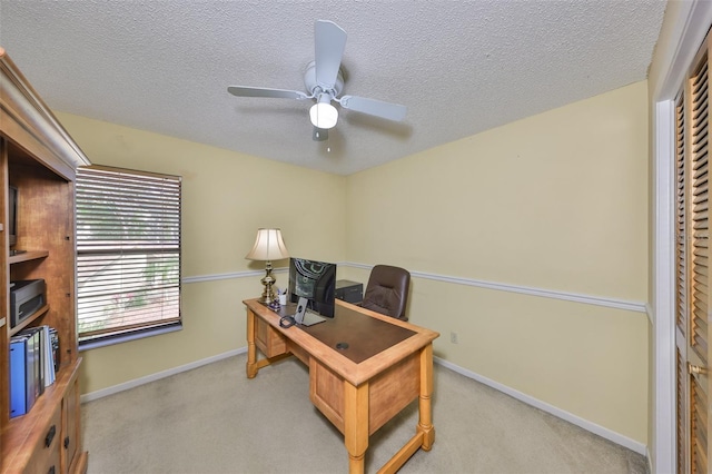 office area with a textured ceiling, ceiling fan, baseboards, and light colored carpet