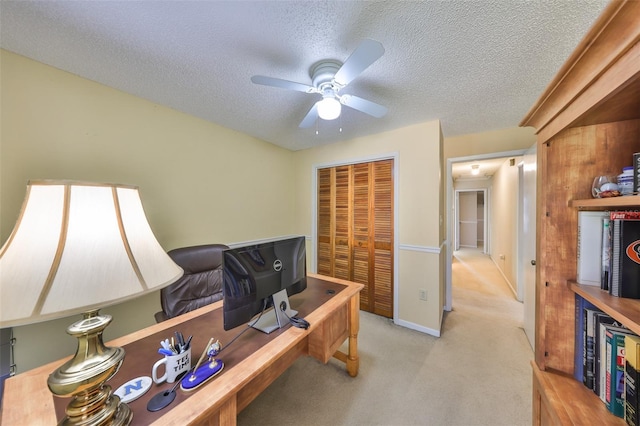 office area with a textured ceiling, ceiling fan, and light colored carpet