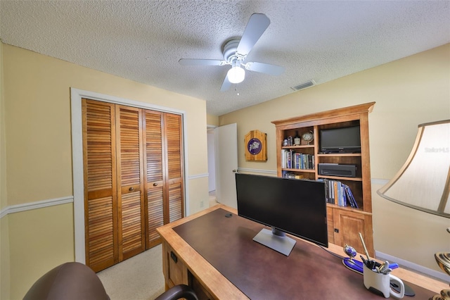 office area featuring visible vents, ceiling fan, carpet flooring, and a textured ceiling