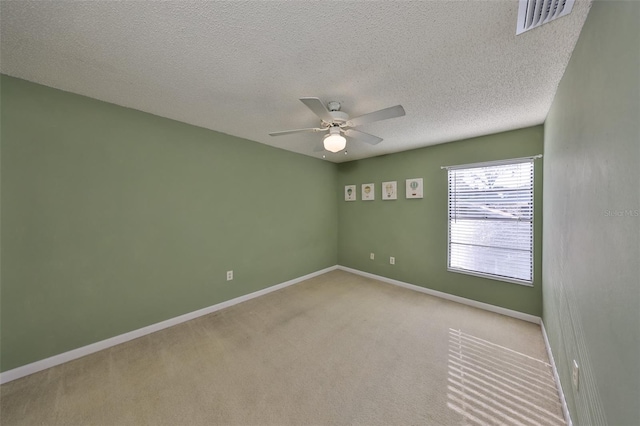 carpeted spare room featuring a textured ceiling, baseboards, ceiling fan, and visible vents