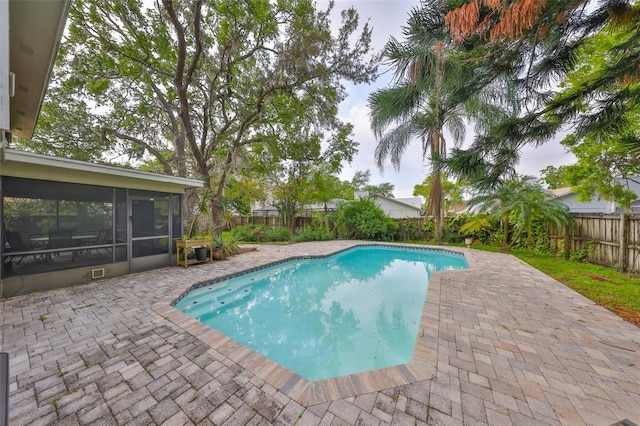 view of pool with a fenced backyard, a fenced in pool, a sunroom, and a patio area