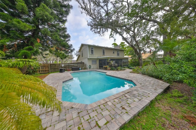 view of swimming pool featuring a sunroom, fence, a fenced in pool, and a patio area