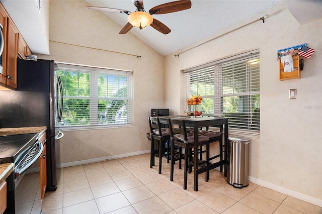 dining area with light tile patterned floors, vaulted ceiling, a ceiling fan, and plenty of natural light