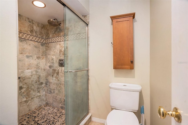 bathroom with baseboards, toilet, and a stall shower