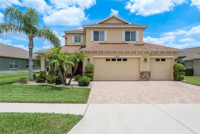 19123 Sunset Bay Dr, Land O Lakes, FL 34638 - view of front of house featuring decorative driveway, a front lawn, roof with shingles, and stucco siding