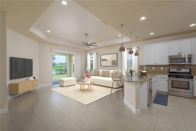 19123 Sunset Bay Dr, Land O Lakes, FL 34638 - kitchen with a peninsula, stainless steel appliances, backsplash, open floor plan, and white cabinets