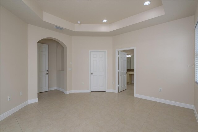 19123 Sunset Bay Dr, Land O Lakes, FL 34638 - unfurnished room with light tile patterned floors, visible vents, baseboards, a raised ceiling, and arched walkways