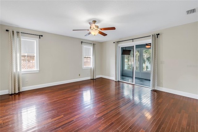 spare room featuring wood-type flooring, a ceiling fan, baseboards, and visible vents